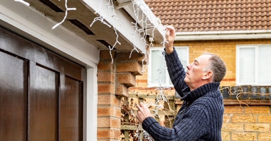 man putting up holiday lights